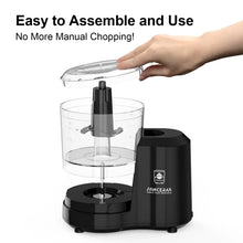 Black electric food chopper with clear bowl and lid being assembled by a hand