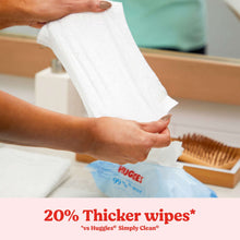 Hands pulling a white baby wipe from a wipes pack, 99% pure water