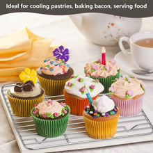 Wire cooling rack with cupcakes and frosted pastries on a stainless roasting tray