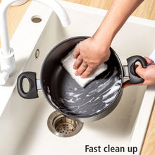 Black non-stick Dutch oven interior being wiped with cloth inside sink