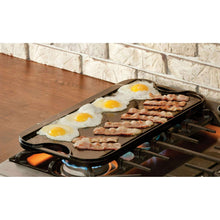 Reversible cast iron griddle on burner cooking eggs and bacon