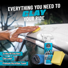Hands holding a yellow clay bar and spray bottle on a car window surface