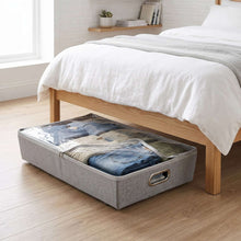 Gray rolling under-bed storage bin with zipper top holding folded jeans on floor