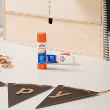 Elmer's all-purpose glue stick standing on craft table near cut shapes