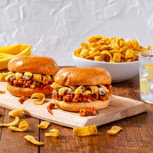 Two burgers with crispy chips and small cup of sauce on a board