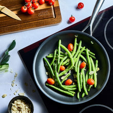 Black non-stick fry pan filled with green beans and cherry tomatoes
