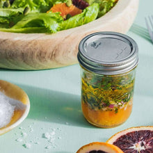 Regular-mouth mason jar with metal lid, filled with herbs, clear glass
