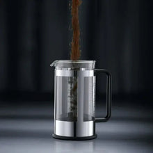 Stainless steel French press coffeemaker with black handle and plunger inside