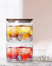 Stacking glass dispenser with acacia lid, layered orange and red drinks, two chrome spigots