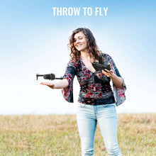 Person holding a mini FPV drone controller while flying a compact quadcopter