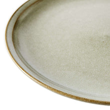 Cream ceramic dinner plate edge detail with speckled glaze and tan rim
