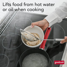 Spider wok strainer draining pieces from hot water; round mesh basket on long handle