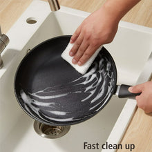 Black nonstick skillet being wiped clean with a cloth
