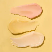 Glossy lip mask swatches in peach and nude tones on a smooth surface.