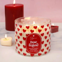 Valentine hearts 3-wick candle jar with lit wicks and centered red label.