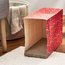 Red cat scratcher paper bag with heart candy pattern, upright on carpet