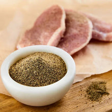 Ground black pepper in a white bowl, with pepper sprinkled on a wooden board