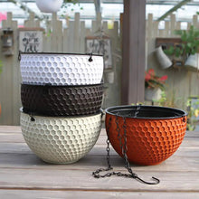 Stacked self-watering hanging planters in dark, white, and orange with chain hangers