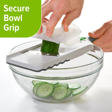 Mandolin slicer with bowl attachment and secure grip base holding cucumber slices