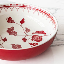Close-up of red stoneware serve bowl interior with floral and bird motifs