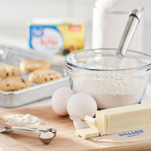 Unsalted butter sticks with eggs and flour on a countertop