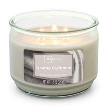 Creamy cashmere scented candle in clear glass jar with three visible flames, front label