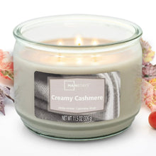 Creamy cashmere scented candle in clear glass jar with three visible flames, centered label