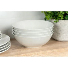 White ceramic coupe bowl with stack of coordinating bowls in a dinnerware set.