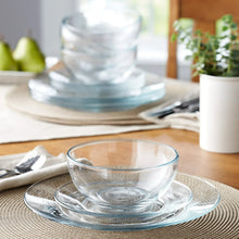 Clear glass dinnerware set with stacked bowls and plates on table, transparent