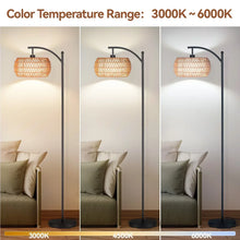 Black arc floor lamp with woven rattan drum shade, glowing light