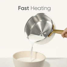 Saucepan with gold handle pouring liquid from stainless interior