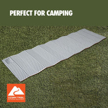 Light gray PE sleeping pad laid out on outdoor grass with raised bump texture