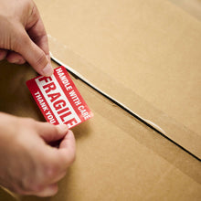 Clear packing tape sealing a cardboard box corner with a cut tab