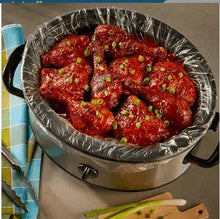 Slow cooker liner in a silver slow cooker with red meat sauce and herbs