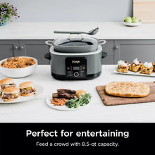 Gray multi-cooker with glass lid and front control panel on a kitchen counter