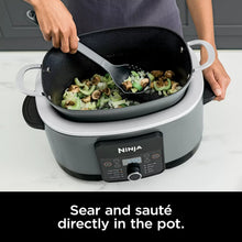 Gray multi-cooker pot with lid open, showing food being stirred
