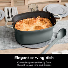 Green multi-cooker with front handles and lid removed, breaded food inside