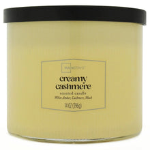 Creamy cashmere scented candle jar with cream wax, black lid, and front label