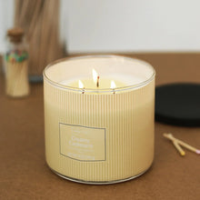 Creamy cashmere scented ribbed candle in cream jar with three lit wicks