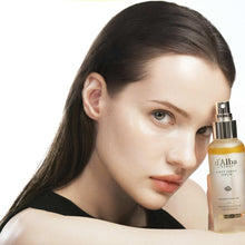 Model holding d'Alba First Spray Serum bottle with gold pump near face