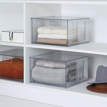 Clear plastic closet drawer with pull handle, holding folded linens and towels
