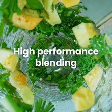 Green smoothie mixture swirling in a clear blender cup with visible chunks