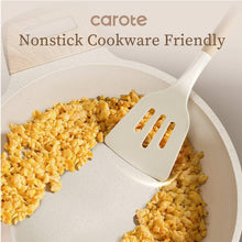 White silicone spatula with light wood handle lifting food from a white nonstick pan