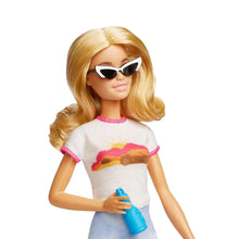 Blonde doll wearing black sunglasses, holding a blue bottle, pink-trim shirt
