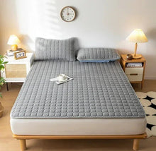 Gray quilted mattress pad with breathable-looking raised pattern and corners.