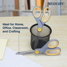 Grey Westcott scissors with yellow grips, lying on a desk near paper