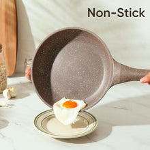 Brown speckled nonstick frying pan with sunny-side-up egg and wood handle
