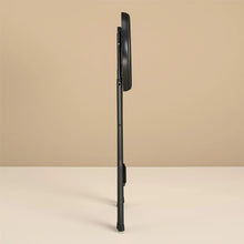 Black folding stool in side view with round seat and tapered leg frame