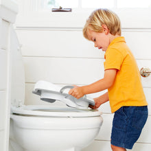 Toddler potty seat on toilet with flip-up lid and built-in handles, light-colored