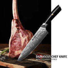 Chef knife with Damascus steel blade and black resin handle, angled beside a cut steak